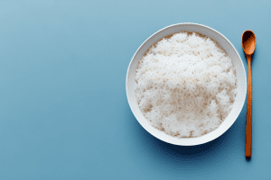 A bowl of cooked white rice with a spoon